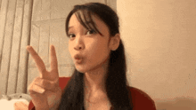 a woman is making a peace sign with her fingers while making a funny face .