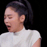 a woman with a ponytail is making a funny face with her mouth open and her eyes closed .