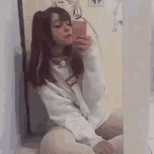 a girl is taking a selfie in front of a mirror in a room .