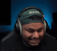 a man wearing headphones and a green hat that says clay smith