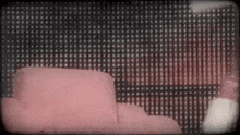 a pink couch is sitting in front of a black and white striped wall .