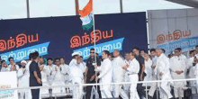 a group of people are standing in front of a large banner holding a flag .