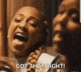a couple of women are laughing and one of them is holding a glass of water .
