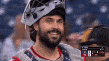 a man wearing a helmet is smiling in front of a scoreboard that says z wood lively