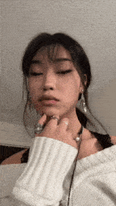 a woman wearing a white off the shoulder sweater and rings