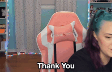 a woman with blue hair is sitting in a pink chair that says luxanow
