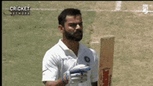 a man with a beard is holding a bat on a field .