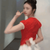 a woman in a red shirt is making a funny face with her finger on her nose .