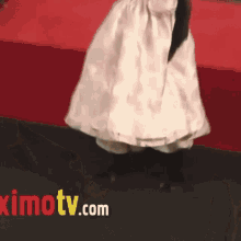 a woman in a white dress is standing on a red carpet next to a ximotv.com logo