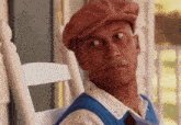 a man wearing a hat and a blue vest is sitting in a rocking chair