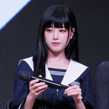 a girl with long black hair is holding a microphone in her hands