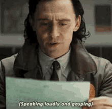 a man in a suit and tie is holding a piece of paper and says `` speaking loudly and gasping '' .