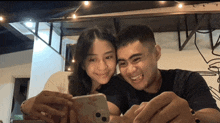 a man and a woman are smiling while looking at a phone