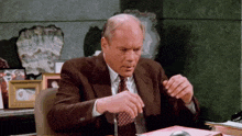 a man in a suit and tie is sitting at a desk looking at papers