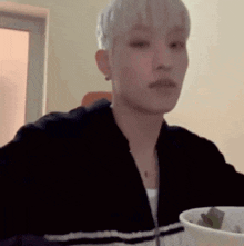a man is sitting at a table eating a salad from a bowl .