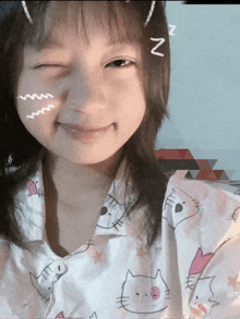 a young girl wearing a hello kitty shirt winks and has a zzz sticker on her forehead