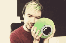 a man with green hair is holding a green pillow in his hands