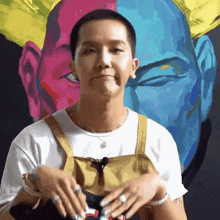a man with a very short haircut is standing in front of a colorful painting