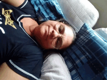 a woman wearing glasses is laying on a bed with a shirt that says ' i love you ' on it
