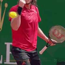 a man in a red shirt is holding a tennis racquet in his right hand .