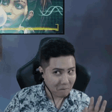 a man wearing headphones is sitting in a chair in front of a screen .