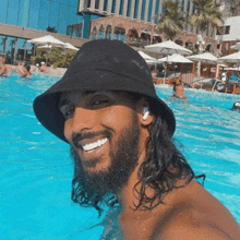 a man with long hair and a beard wearing a black hat is swimming in a pool