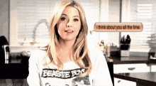 a woman wearing a beastie boys shirt is talking on a phone
