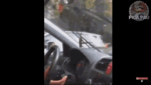 a person is driving a car with a broken windshield and a broken steering wheel .