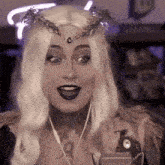 a woman wearing a wig and a crown is talking into a microphone .