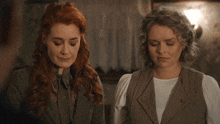 two women are standing next to each other with their eyes closed .