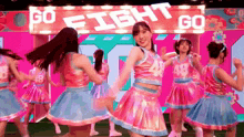 a group of cheerleaders are dancing on a stage in front of a sign that says go fight go .