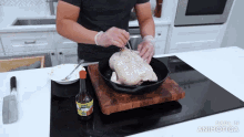 a man is cooking a chicken in a cast iron skillet with a bottle of knorr sauce next to him