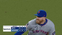 a man wearing a new york mets jersey stands on a field