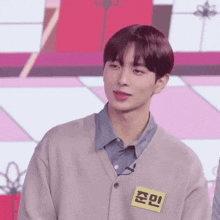 a young man wearing a sweater and a name tag with chinese writing on it .