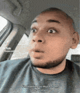a man with a beard is sitting in a car with his mouth open and a surprised look on his face .