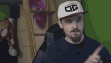 a man with a beard wearing a white hat with the letter og on it