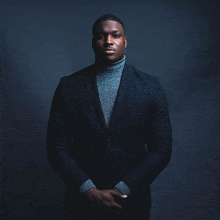 a man in a suit and turtleneck is posing for a picture .