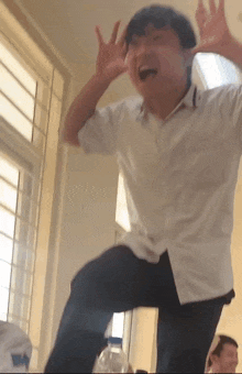 a man in a white shirt is making a funny face with his hands