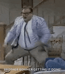 a man in a suit and tie is standing on a stool and talking on a cell phone .