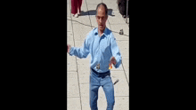 a man in a blue shirt and blue jeans is walking down the street .
