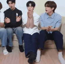 a group of young men are sitting on a couch with their legs crossed .