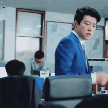a man in a blue suit and tie stands in a room