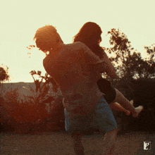 a man is carrying a woman in his arms with the letter l on the bottom