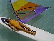 a woman laying on a surfboard with a sail