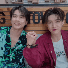 two young men holding hands in front of a sign that says g love