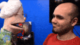 a man in a red shirt looks at a puppet with glasses