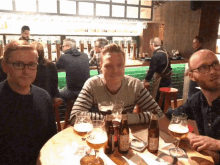 three men are sitting at a table with bottles of lief beer