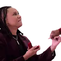 a woman in a maroon jacket is holding a red box with a ring in it