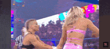 a woman in a pink top is standing next to another woman in a wrestling ring ..
