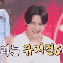 a man in a white shirt is smiling in front of a red background with chinese writing on it .